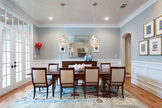 dining area featuring ornamental molding, wood finished floors, visible vents, and arched walkways