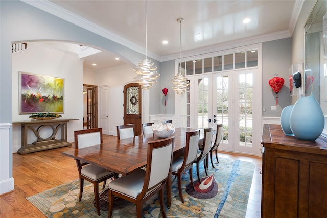 dining area with light wood finished floors, ornamental molding, recessed lighting, french doors, and arched walkways