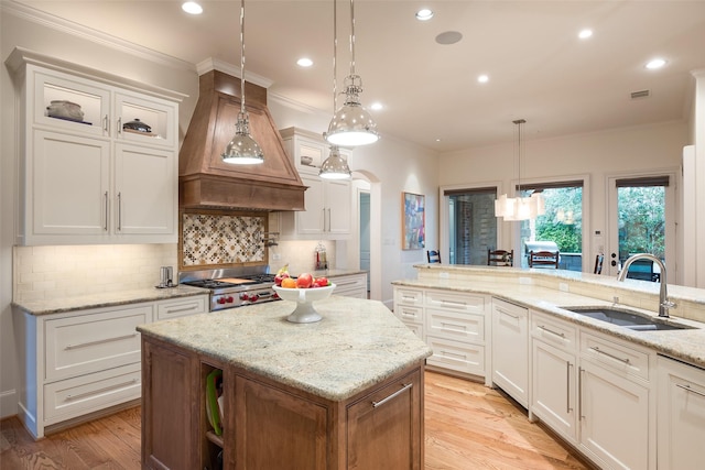 kitchen featuring stainless steel gas cooktop, custom exhaust hood, arched walkways, a sink, and crown molding