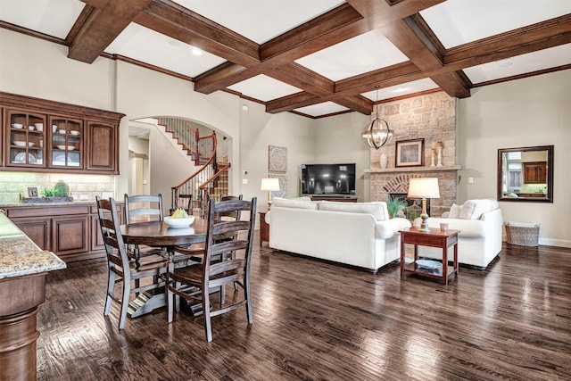 dining space with beamed ceiling, dark wood-style flooring, coffered ceiling, arched walkways, and stairs