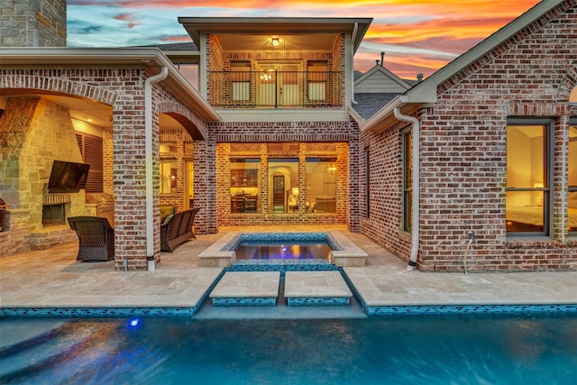 exterior space featuring brick siding, a patio, and a balcony