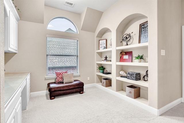 sitting room with visible vents, built in shelves, baseboards, and carpet