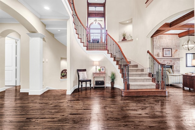 entryway with baseboards, a stone fireplace, wood finished floors, and a towering ceiling