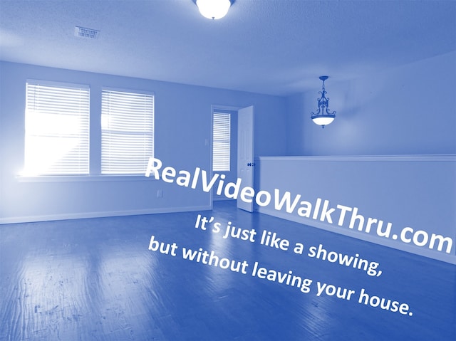 interior space featuring visible vents, baseboards, a textured ceiling, and wood finished floors