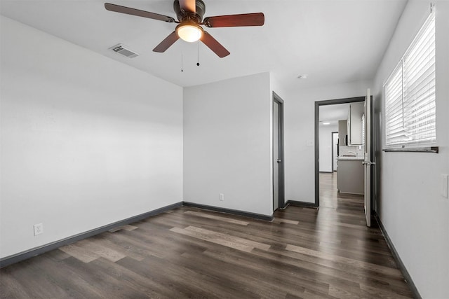 spare room with a ceiling fan, dark wood finished floors, and baseboards
