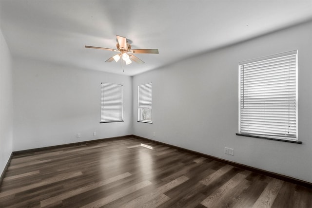 spare room with ceiling fan, dark wood-style flooring, and baseboards