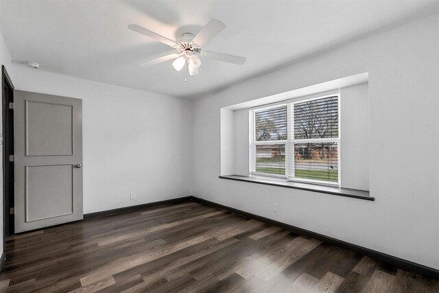 empty room featuring a ceiling fan, dark wood-type flooring, a smoke detector, and baseboards