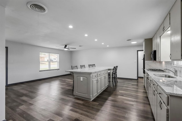 kitchen featuring a sink, a center island, a ceiling fan, baseboards, and recessed lighting