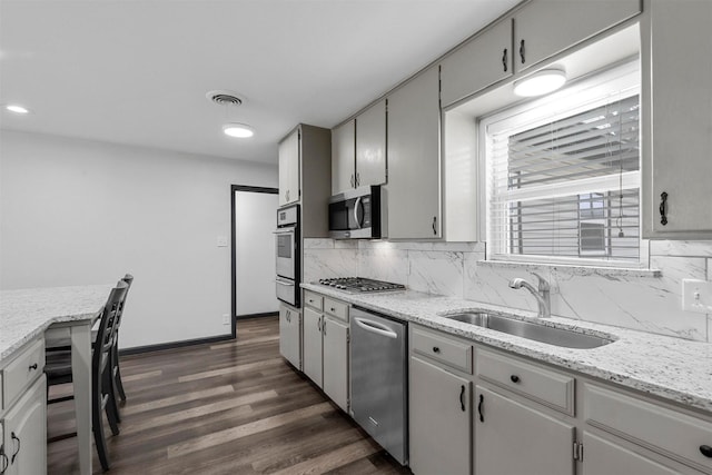 kitchen with appliances with stainless steel finishes, a sink, a warming drawer, tasteful backsplash, and dark wood finished floors
