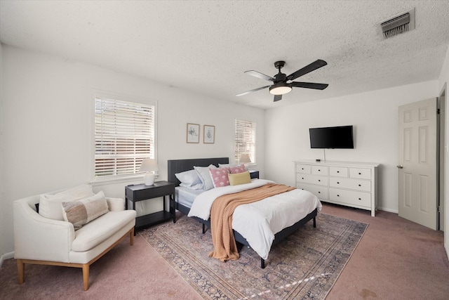 bedroom featuring visible vents, a textured ceiling, carpet flooring, and a ceiling fan