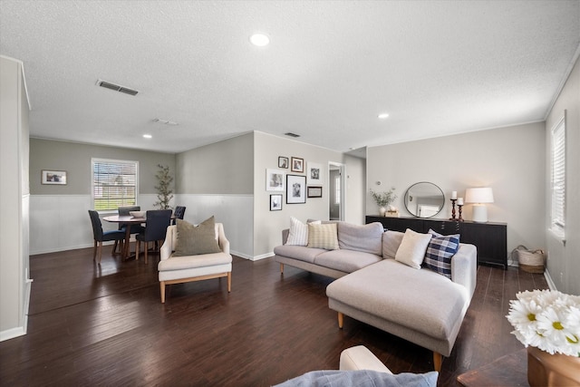 living area featuring visible vents, a textured ceiling, and wood finished floors