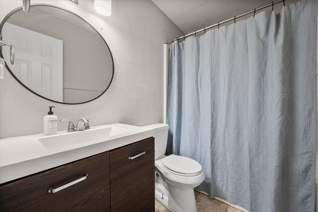 bathroom featuring vanity, toilet, a textured wall, and a textured ceiling