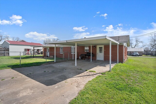 view of front facade with driveway, a carport, fence, a front yard, and brick siding