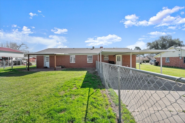 rear view of house with a yard, fence, and brick siding