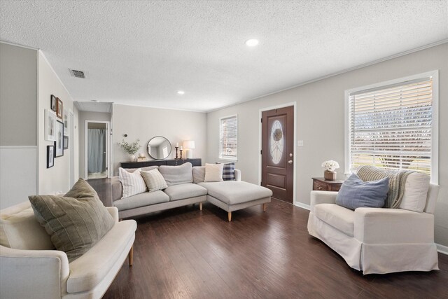 living room with dark wood-type flooring, a healthy amount of sunlight, visible vents, and a textured ceiling