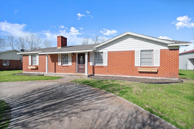 ranch-style home with brick siding, a chimney, and a front lawn