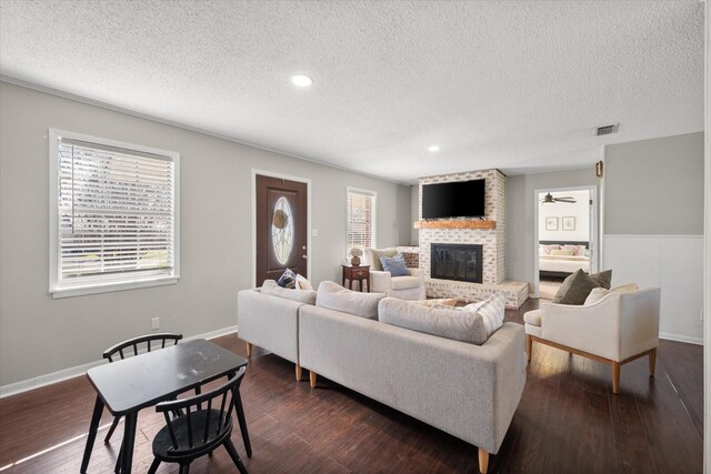 living area featuring visible vents, a fireplace, a textured ceiling, and dark wood-type flooring