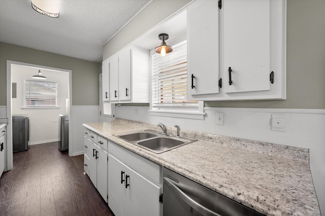 kitchen featuring washing machine and clothes dryer, dark wood-type flooring, light countertops, white cabinets, and a sink