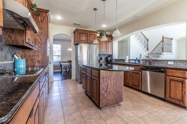 kitchen with visible vents, under cabinet range hood, a center island, arched walkways, and appliances with stainless steel finishes