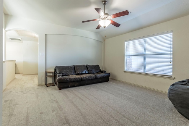 carpeted living area featuring lofted ceiling, baseboards, arched walkways, and ceiling fan