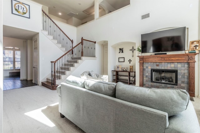 living area featuring stairs, visible vents, a towering ceiling, and carpet flooring