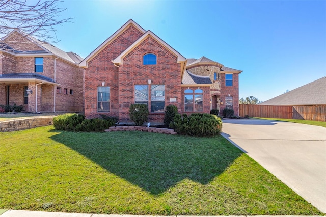 traditional home featuring brick siding, a front lawn, and fence