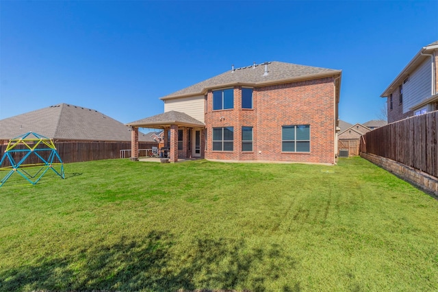 rear view of property featuring brick siding, a patio area, a lawn, and a fenced backyard