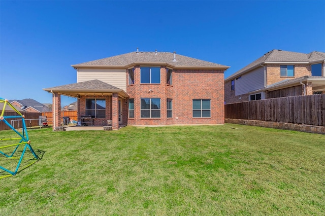 back of property featuring roof with shingles, a fenced backyard, a lawn, a patio area, and brick siding