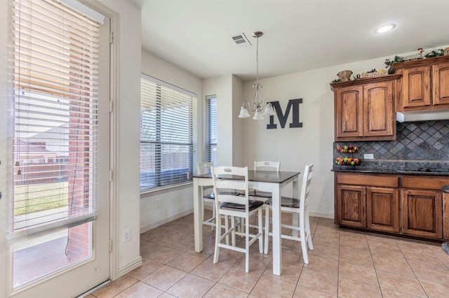 dining area featuring light tile patterned floors, visible vents, baseboards, and an inviting chandelier