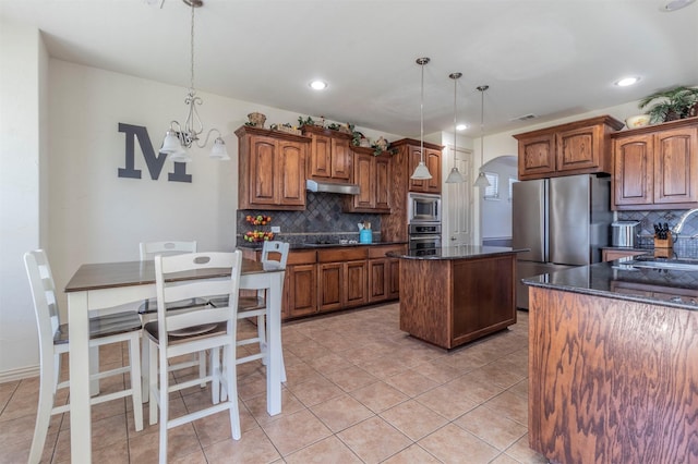 kitchen with visible vents, under cabinet range hood, a kitchen island, stainless steel appliances, and arched walkways