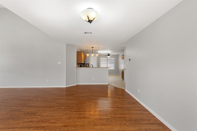 unfurnished living room featuring visible vents, baseboards, ceiling fan, and light wood finished floors