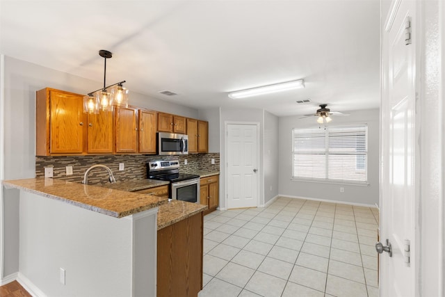 kitchen featuring visible vents, stainless steel appliances, a peninsula, brown cabinetry, and decorative backsplash