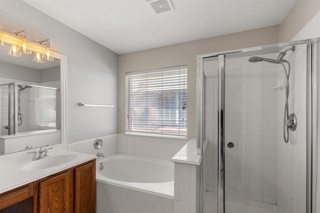 bathroom with vanity, visible vents, a bath, and a stall shower
