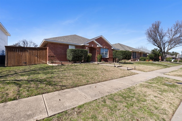 view of front of property featuring brick siding, a shingled roof, a gate, and a front lawn