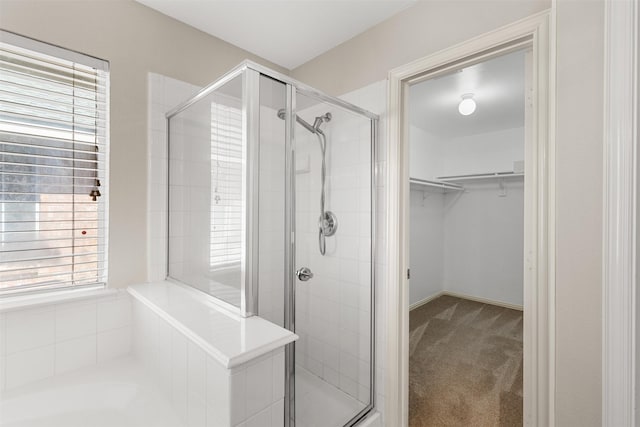 bathroom featuring a walk in closet, a garden tub, and a stall shower