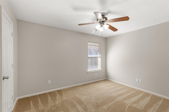 spare room featuring baseboards, a ceiling fan, and light colored carpet