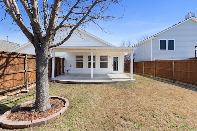 rear view of house with a fenced backyard, a patio area, and a yard
