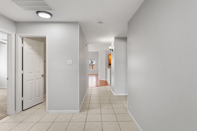 hall featuring light tile patterned floors, baseboards, and visible vents