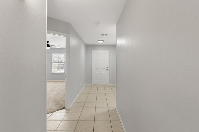 hallway with light tile patterned flooring, light carpet, and baseboards