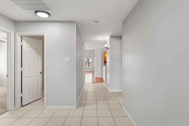 hall featuring light tile patterned flooring, baseboards, and visible vents