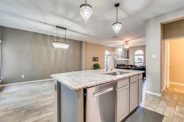 kitchen with a ceiling fan, a fireplace, a sink, dishwasher, and open floor plan