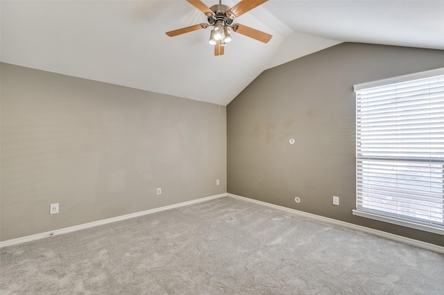 empty room featuring baseboards, lofted ceiling, carpet floors, and ceiling fan