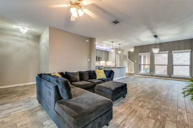 living area with visible vents, baseboards, ceiling fan, and light wood finished floors