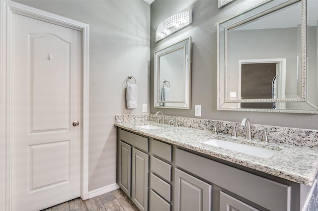 full bath featuring a sink, baseboards, wood finished floors, and double vanity