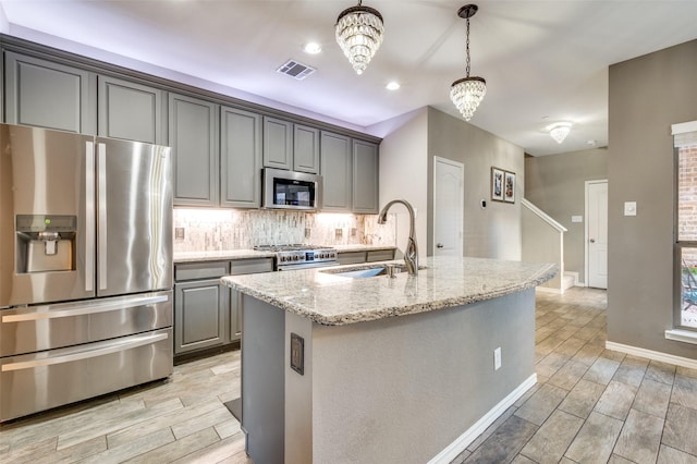 kitchen with light stone counters, visible vents, gray cabinets, a sink, and appliances with stainless steel finishes