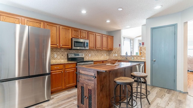 kitchen with a center island, a breakfast bar area, light wood-style flooring, stainless steel appliances, and a sink