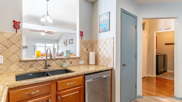 kitchen with brown cabinets, dishwasher, light stone countertops, and a sink