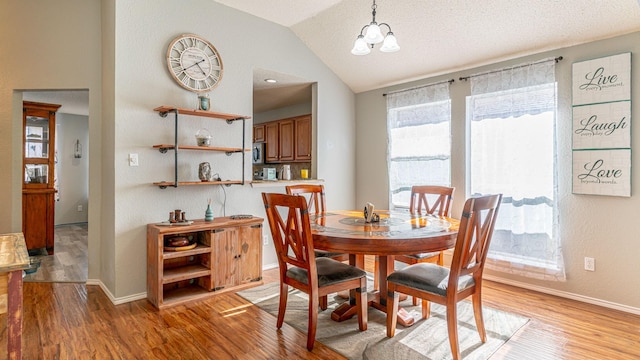 dining room with light wood-type flooring, baseboards, and vaulted ceiling