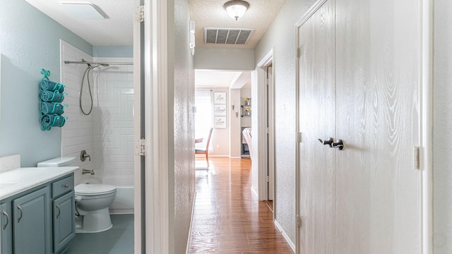 full bath featuring visible vents, a textured ceiling, vanity, and toilet