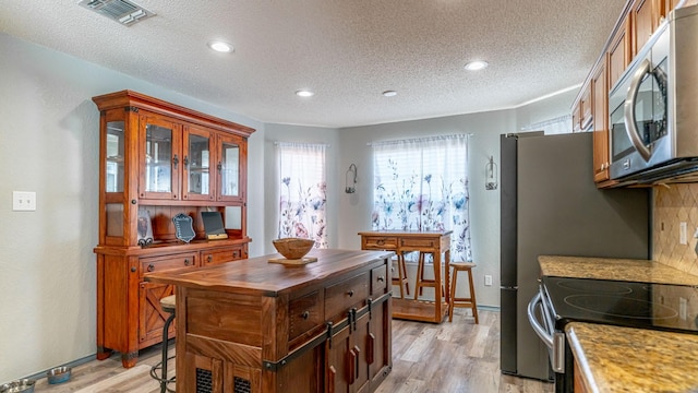 kitchen with visible vents, butcher block countertops, light wood-style flooring, appliances with stainless steel finishes, and a textured ceiling